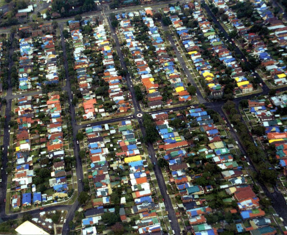 Coloured tarpaulin cover the roofs of houses damaged during the Sydney Storms, 1999