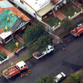 Coloured tarpaulin cover the roofs of houses damaged during the Sydney Storms, 1999