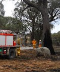 Firefighters survey the burnt out area after extinguishing the fire on Clements Road, near Woodstock